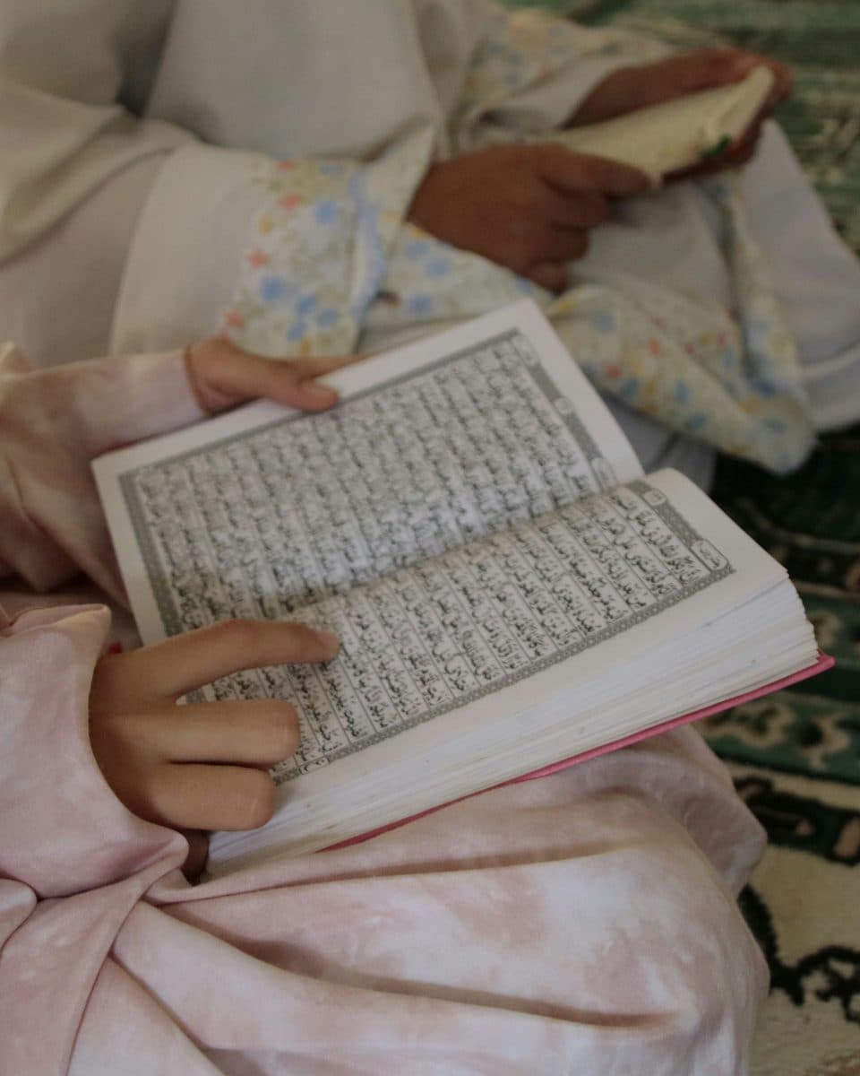 A child reading the Quran, following the lines with her finger